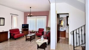 A living room with a red sofa, a coffee table, and a TV. There is a staircase leading to another room. - Villa Christodoula (Polis)