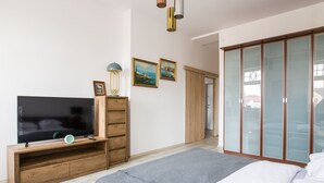 A bedroom with a bed, a TV on a wooden stand, a wardrobe, and two framed pictures on the wall. - Deer Apart (Cieszyn)
