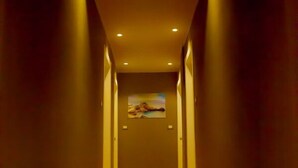 Un pasillo con alfombra roja, iluminación empotrada y un cuadro en la pared.