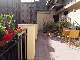 Un pequeño patio al aire libre con macetas, un cerco de madera y sillas amarillas.