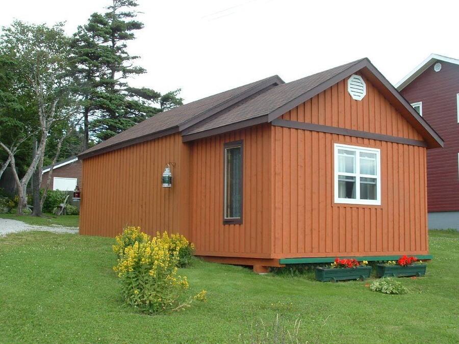 A wooden cabin with a pitched roof, a front door, and a small window.
