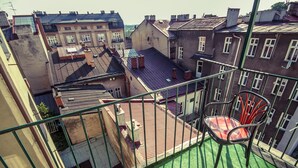 A balcony with a green surface, a metal railing, and a red chair. - Upper Apart (Cieszyn)