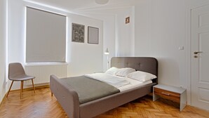A bedroom with a bed, a chair, a bedside table, and a window. - Upper Apart (Cieszyn)
