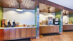 Un vestíbulo de hotel moderno con mostrador de recepción, máquinas de café y una pantalla digital.