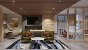 Una sala de estar moderna con chimenea, sillones con cojines verde y rojo, una mesa de centro redonda y una pared de acento de piedra.