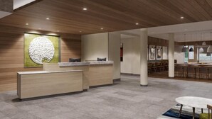 Un área de recepción moderna con techo de madera, una mesa de recepción y un espacio de estar con mesas y sillas.