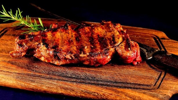 A grilled steak on a wooden cutting board with a knife. - La Favorita Apricale B&B (Apricale)