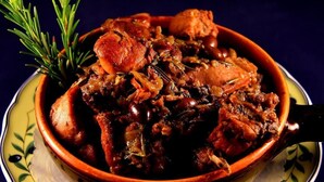 Eine Schüssel Eintopf mit Fleisch und Gemüse, garniert mit einem Rosmarin-Zweig.