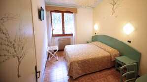 Ein Schlafzimmer mit einem Bett, einem Sessel, einer Heizung und einem Fenster mit Vorhängen.