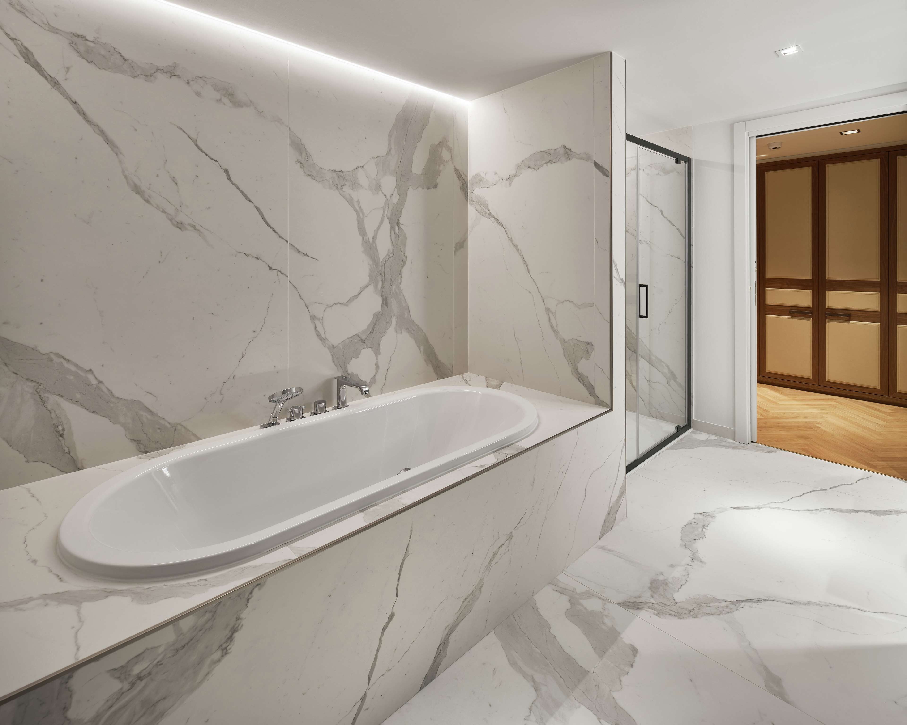 A modern bathroom with a marble vanity, a bathtub, and a glass shower enclosure.