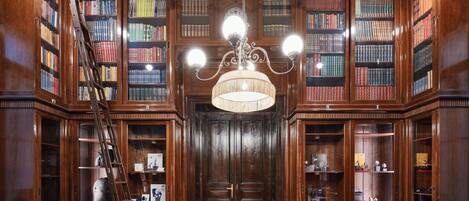 A library with wooden bookshelves, a chandelier, and a ladder.