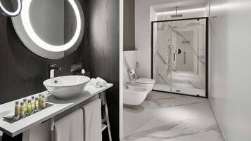 A modern bathroom with a large mirror, white sink, and a glass-enclosed shower.