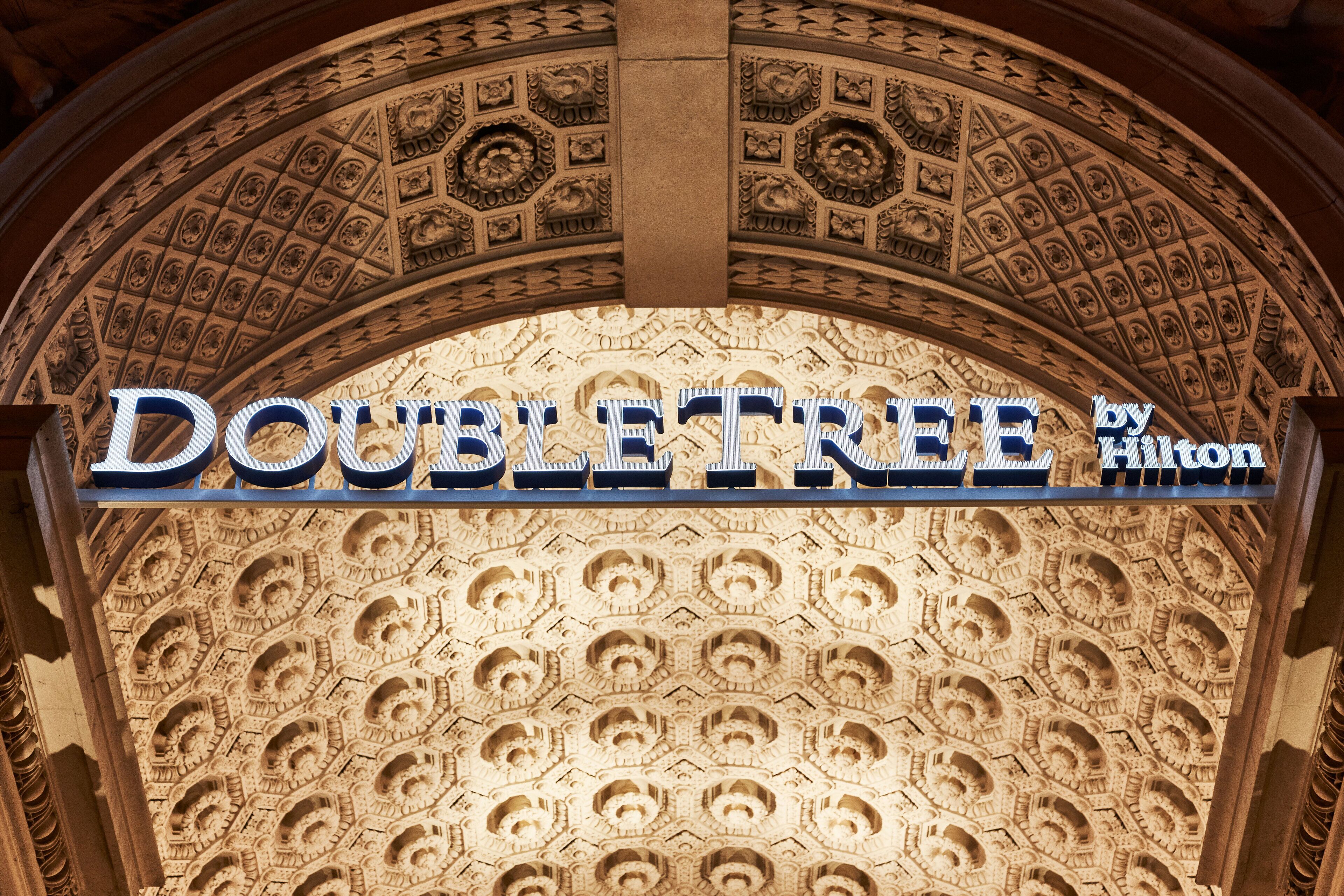 A hotel sign with intricate ceiling carvings and the name "DOUBLETREE by Hilton".