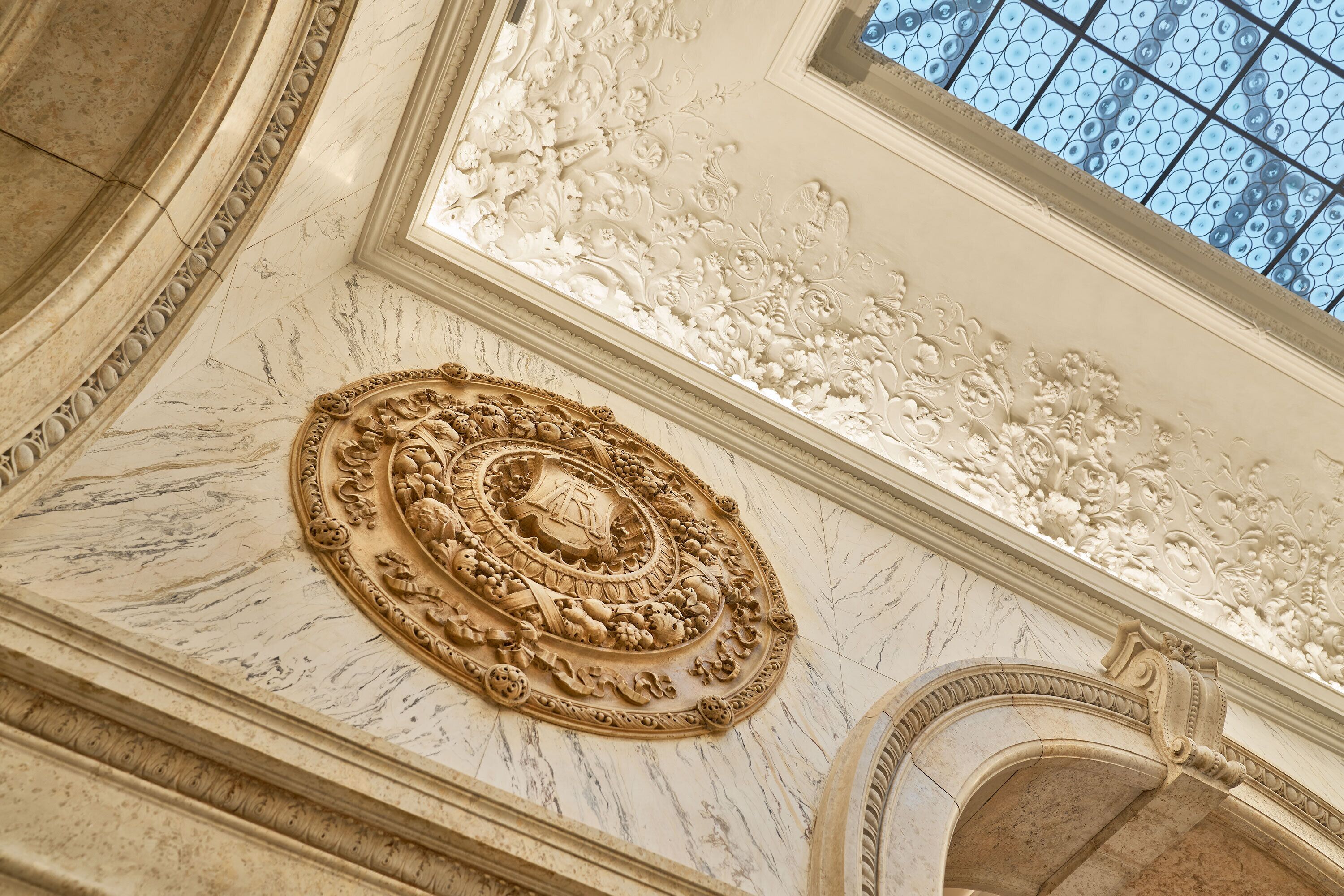 A detailed architectural ceiling with ornate carvings and a skylight.