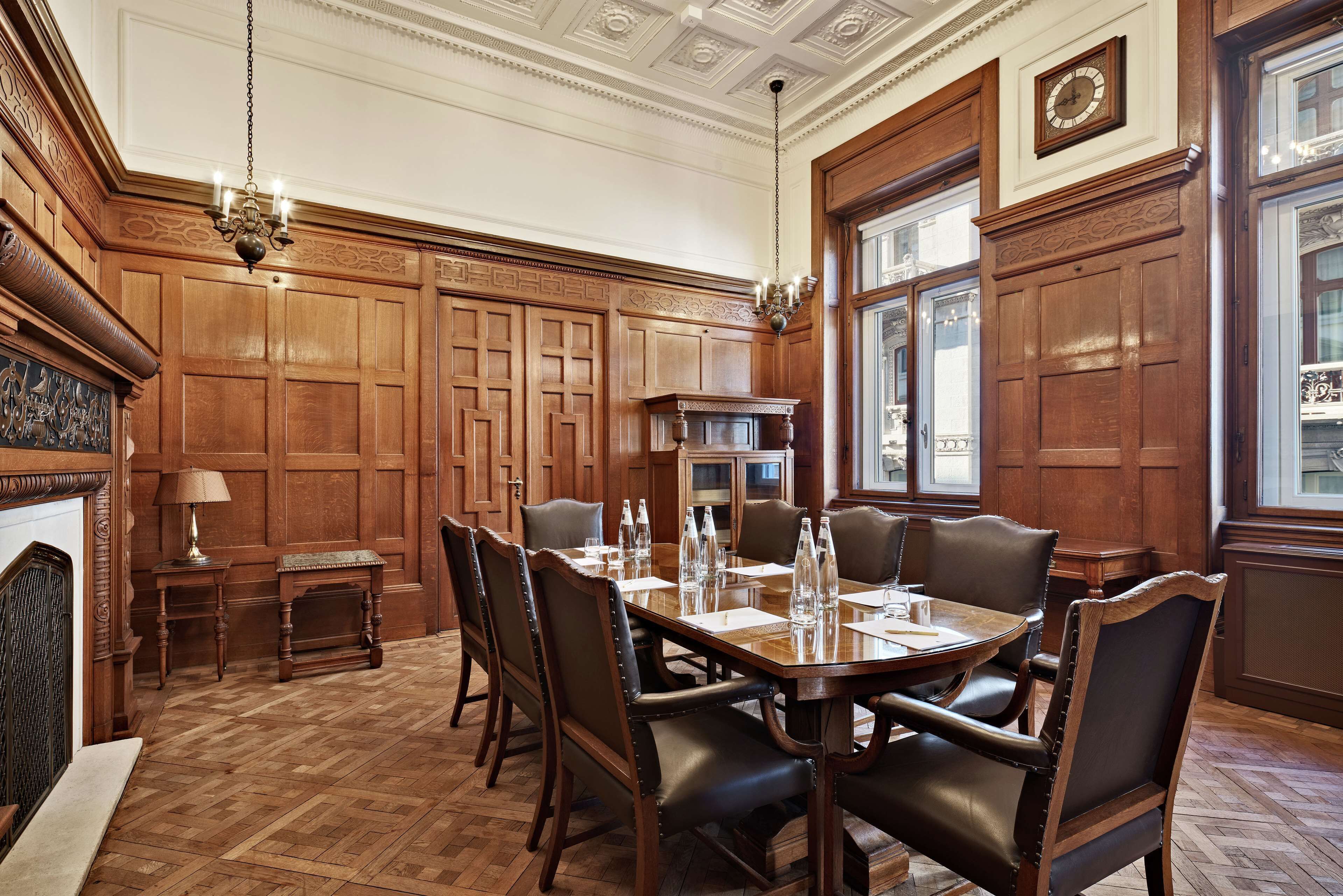 Un comedor formal con una mesa y sillas de madera, un candelabro y una chimenea.