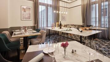 A hotel dining area with a long table, chairs, and a chandelier.
