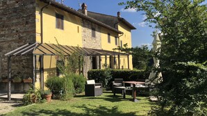 Un bâtiment jaune avec une façade en pierre, un patio couvert et du mobilier d’extérieur.