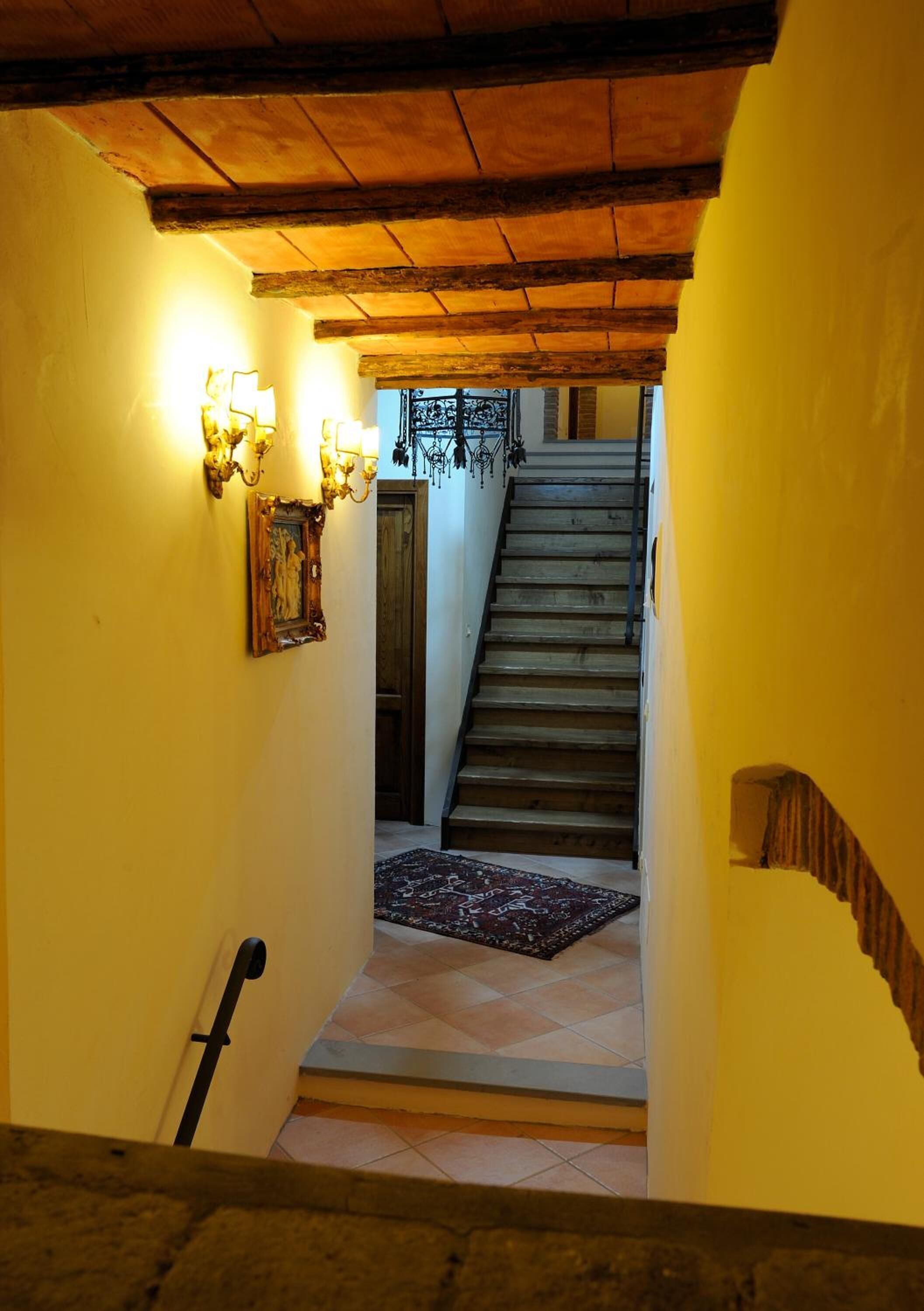 Una escalera de madera con barandilla que lleva a una plataforma con alfombra estampada.