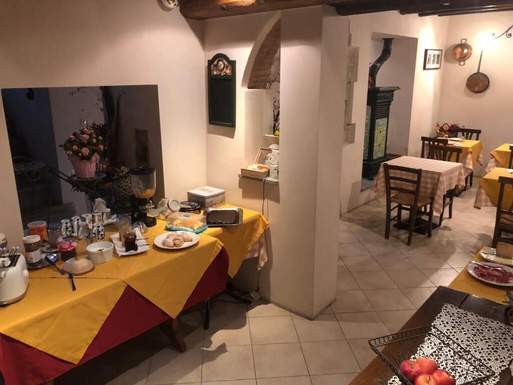 Zona de dinar amb taules preparades per a un àpat, zona de cuina amb electrodomèstics i taula de dinar amb estovater de color groc.