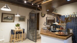 Une cuisine avec des tabourets de bar en bois, une machine à café et un panier de fruits posé sur le comptoir.