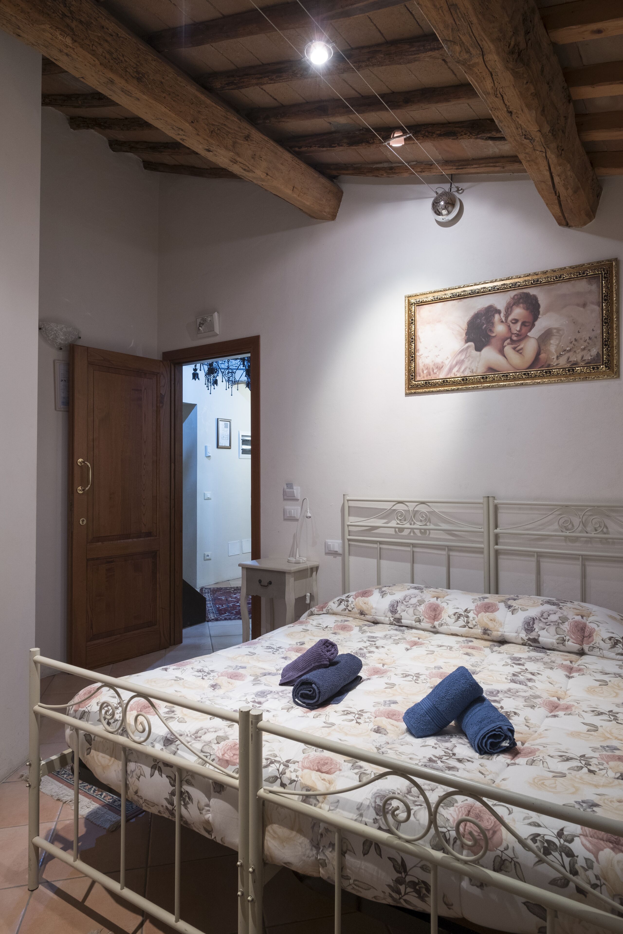 A bedroom with a bed, wooden door, and a framed picture on the wall.