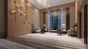 Um hall amplo com design moderno, apresentando uma grande área de estar, um lustre decorativo e uma janela grande com vista.
