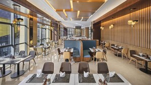 Um restaurante moderno com pé-direito alto, amplas janelas e um balcão central.