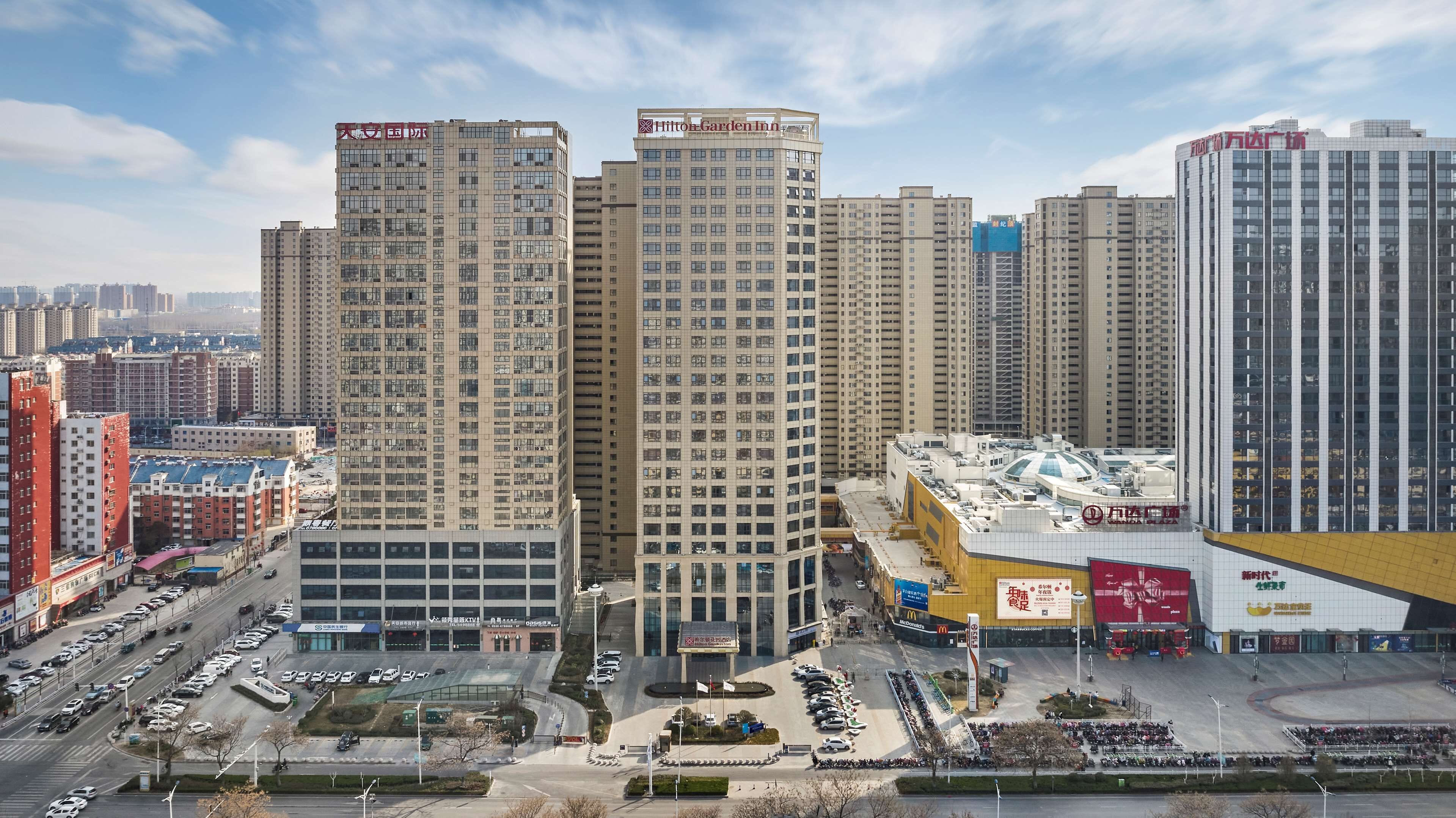 Un hôtel de grande hauteur, avec de nombreux étages, une cour intérieure et un parking pouvant accueillir plusieurs voitures.
