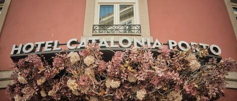 Das Hotel Catalonia Porto, mit einem Schild über dem Eingang und einer Blumendekoration darunter.