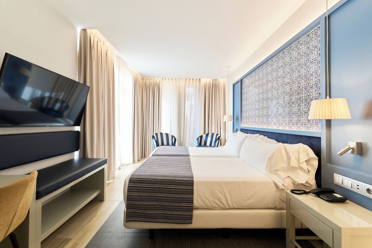 Ein Hotelzimmer mit Bett, Fernseher, Schreibtisch und Lampe.