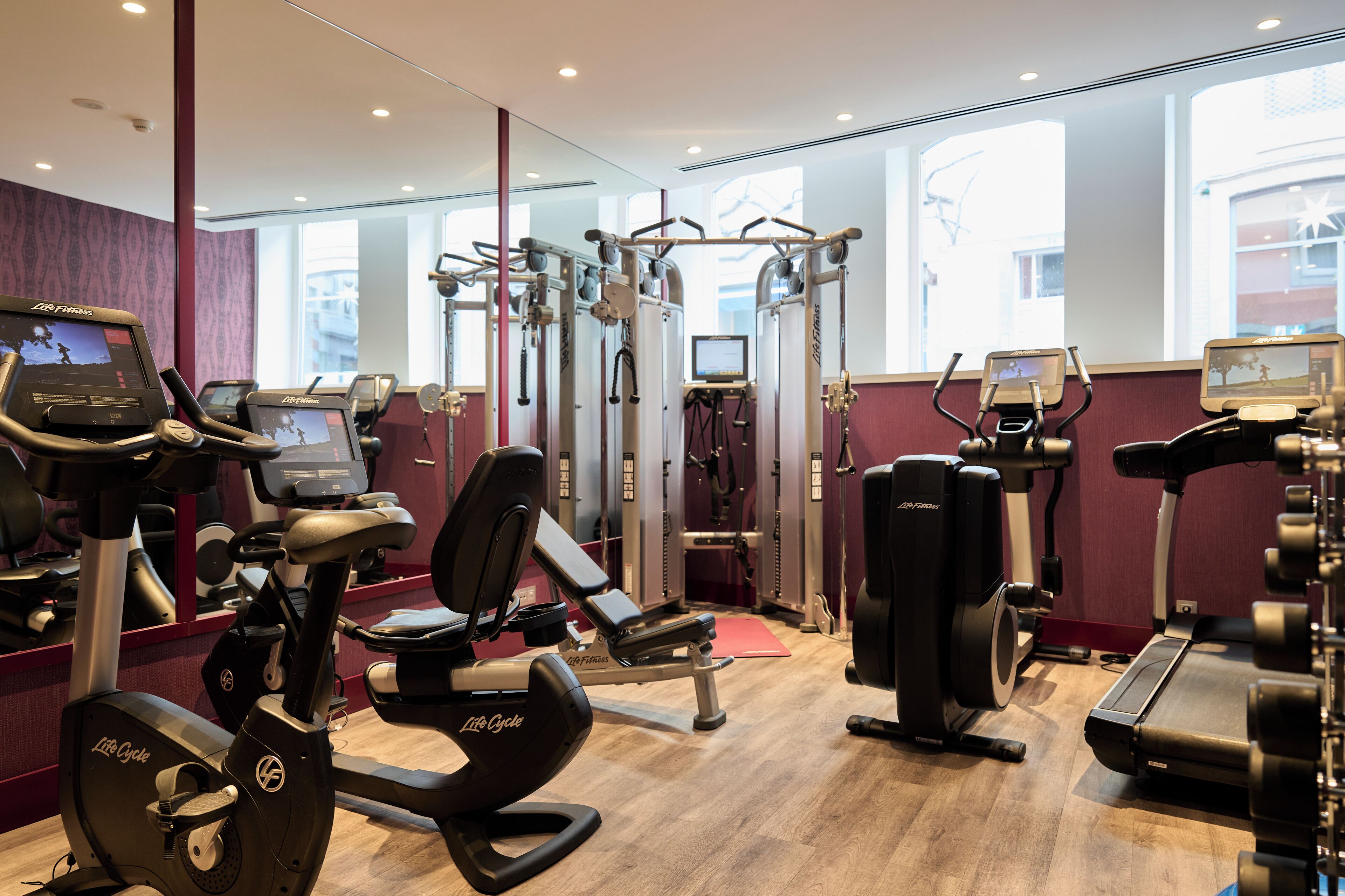 A gym with cardio machines, weight training equipment, and a mirror wall.