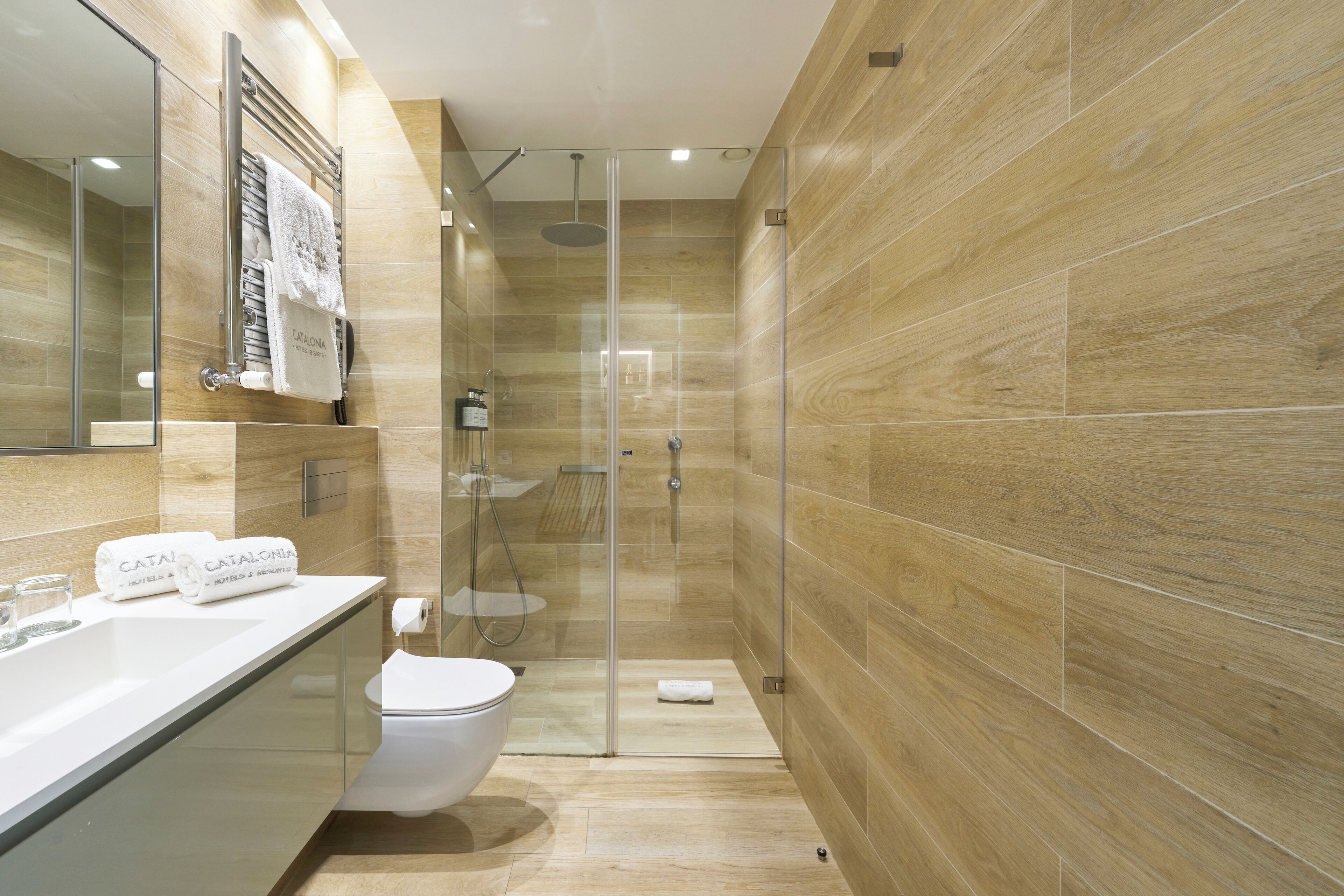 A modern bathroom with a glass-enclosed shower, a white sink, and a toilet.