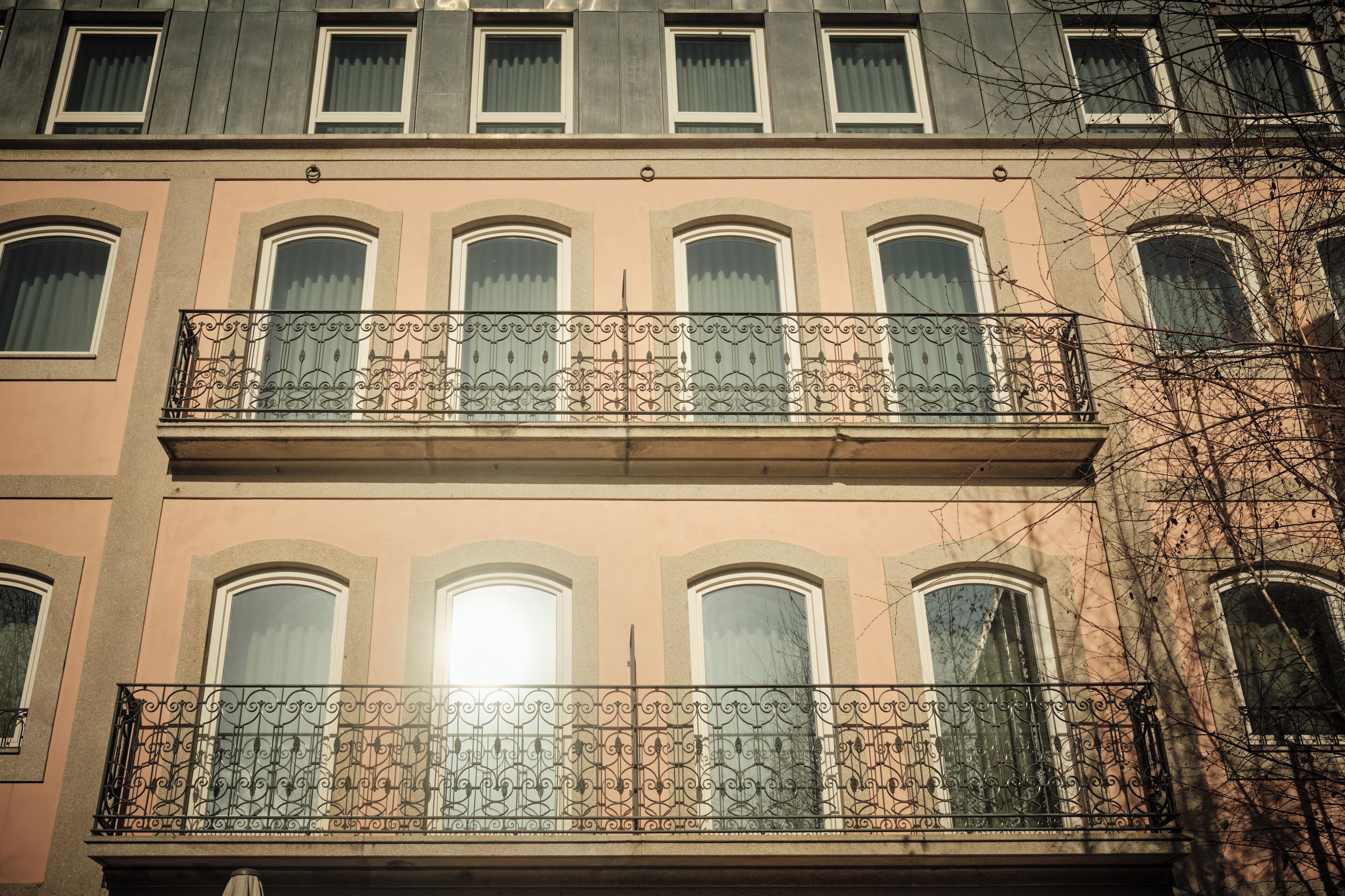 Ein mehrstöckiges Gebäude mit einem Balkon und aufwendigen schmiedeeisernen Geländern.