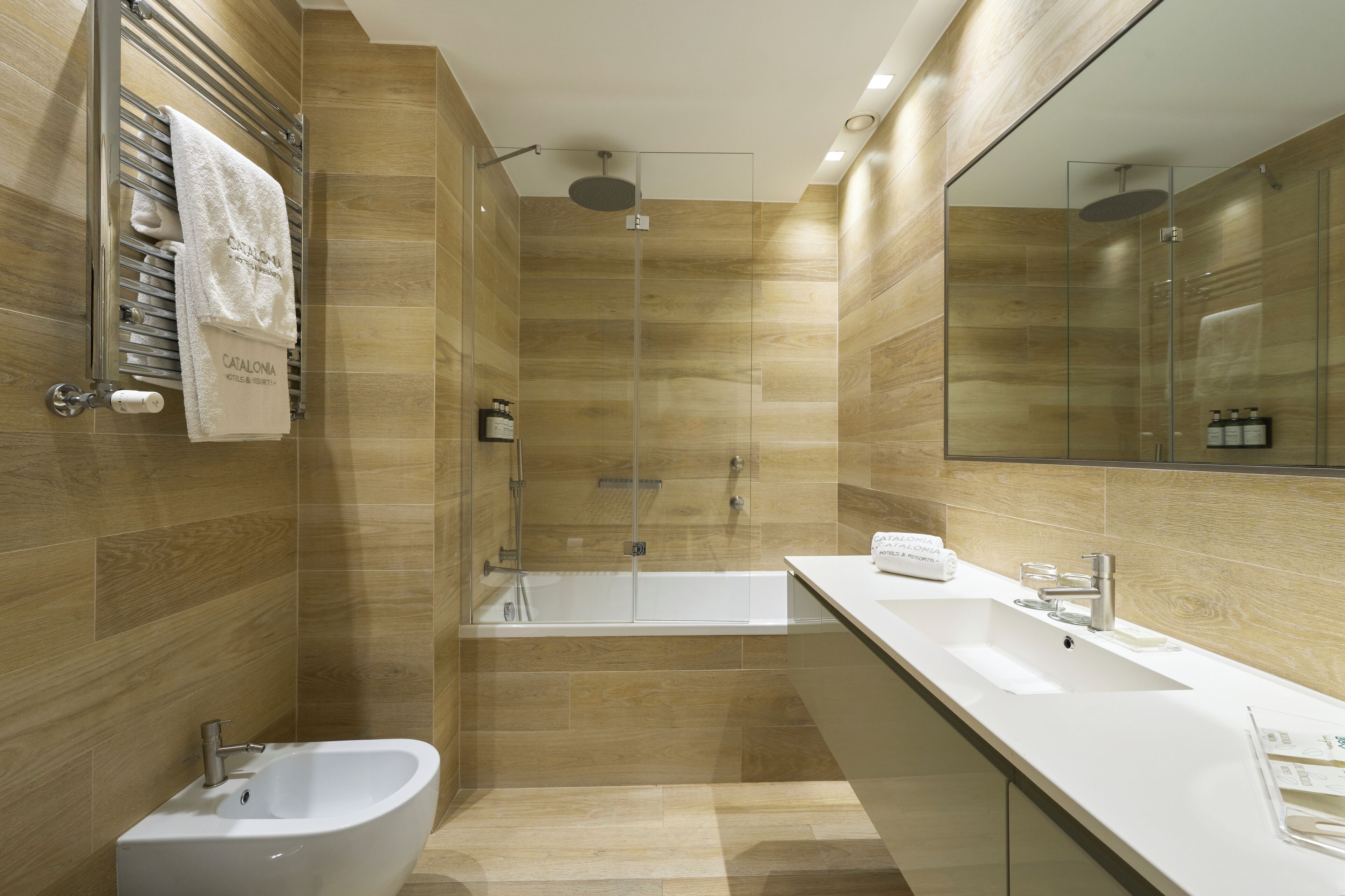 Un bany modern amb una banyera autònoma, un lavabo integrat i una dutxa amb envàs de vidre.