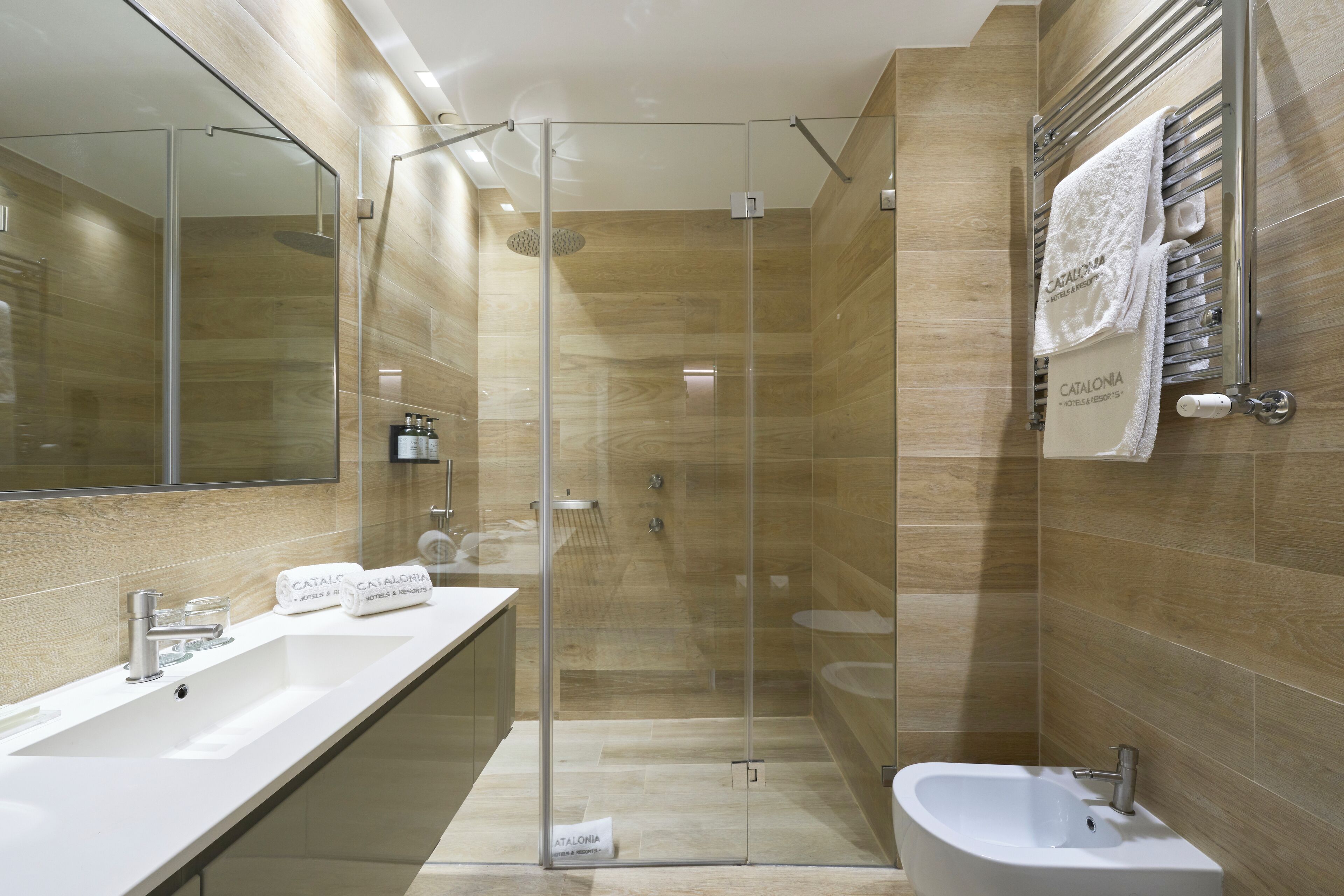 A modern bathroom with a glass-enclosed shower, a white sink, and a bidet.
