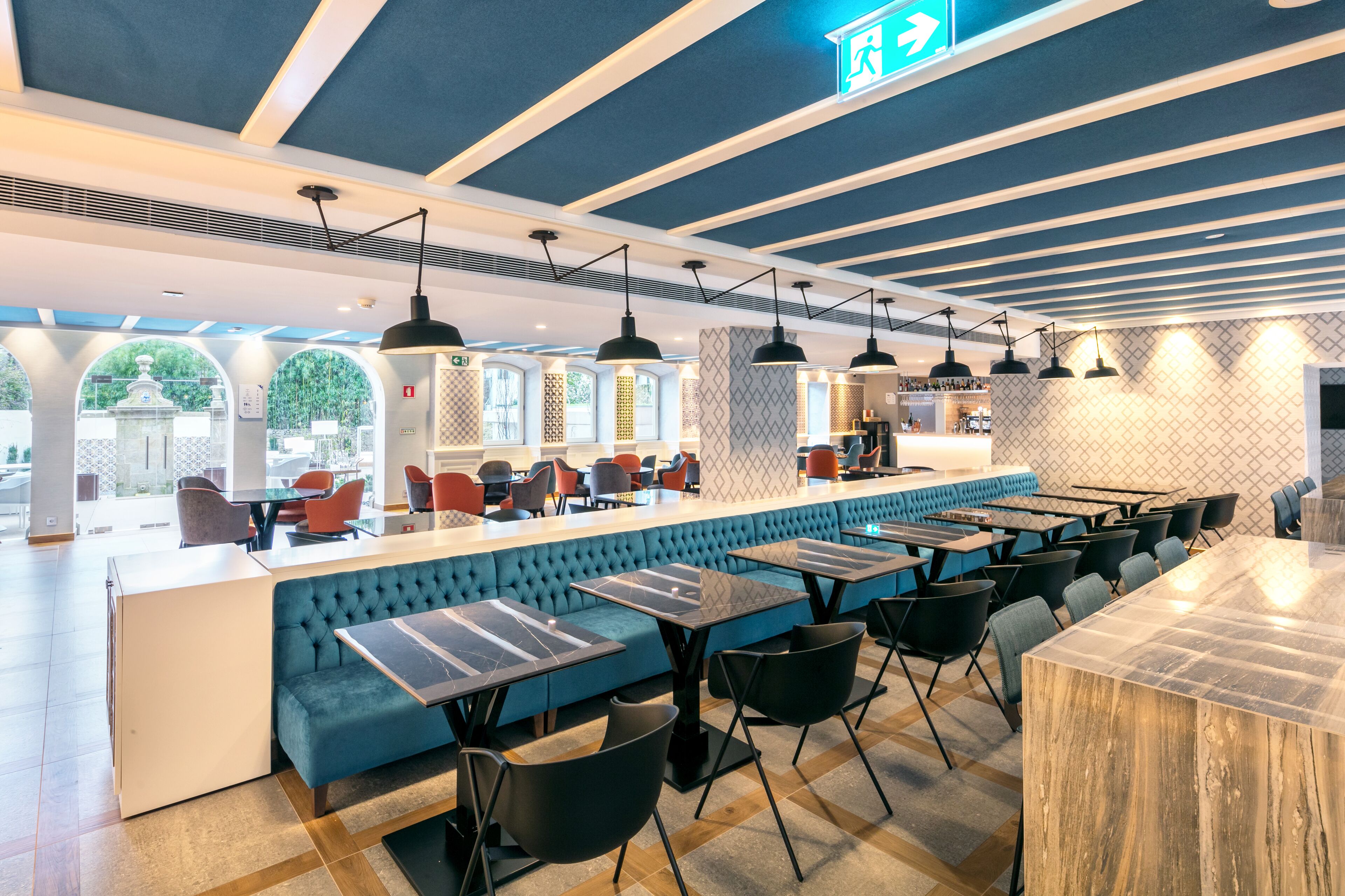 A modern restaurant with a central bar, seating areas, and a patterned wall.