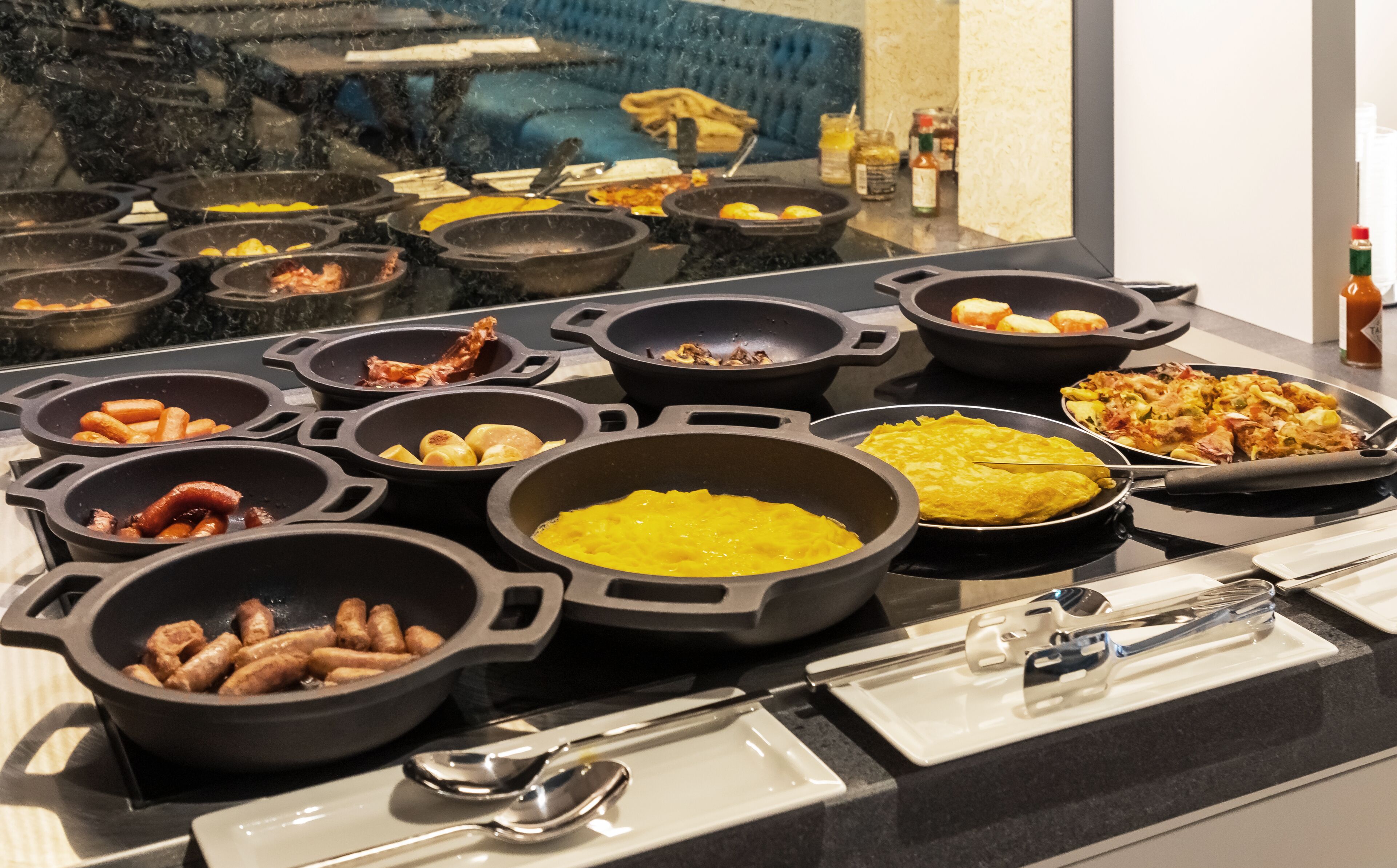 A buffet with various dishes in black serving containers.