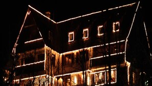 A large, multi-story building with a steeply pitched roof, illuminated by warm interior lighting. - Hotel Merkurwald-Restaurant Wolpertinger (Baden-Baden)