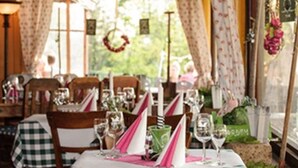 A restaurant with checkered tablecloths, neatly set tables with wine glasses, and a view of greenery outside. - Hotel Merkurwald-Restaurant Wolpertinger (Baden-Baden)