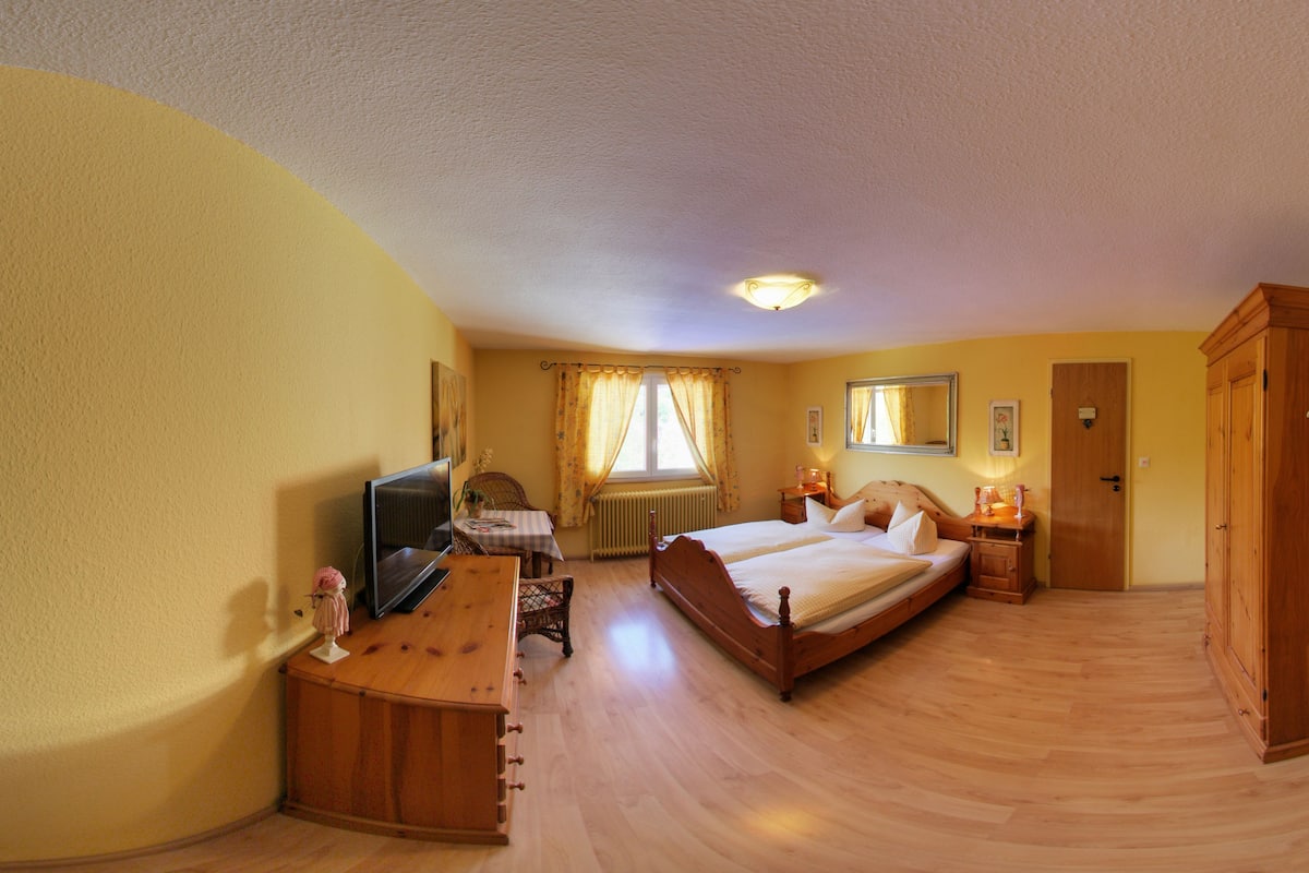 A bedroom with two beds, a desk, a chair, a radiator, and a wardrobe.