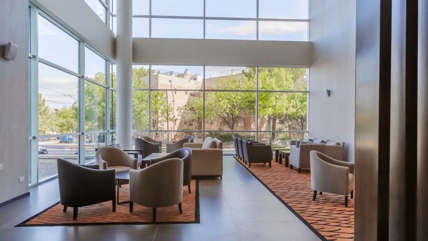 A modern indoor space with large windows, seating areas, and a view of the outside. - Hilton Garden Inn Neuquen (Neuquén)