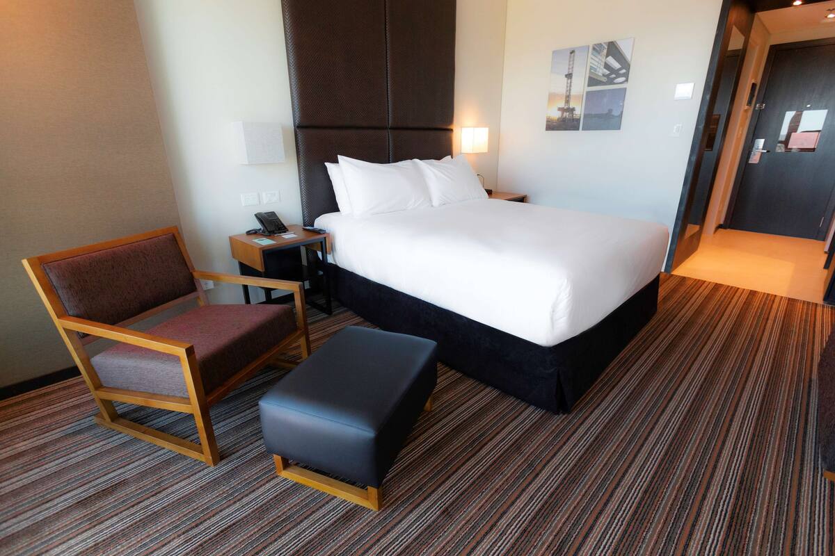 Ein Hotelzimmer mit einem Bett, einem Sessel, einem Schreibtisch und einem kleinen Tisch.
