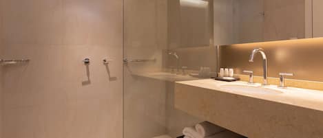 A modern bathroom with a glass-enclosed shower, a large mirror, and a beige countertop.