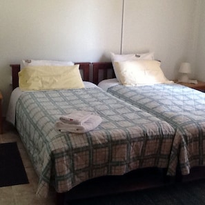 A double bed with a plaid bedspread, a yellow pillow, and a white pillow.