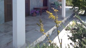 Un espacio al aire libre cubierto con paredes de piedra, contraventanas de madera y un banco.