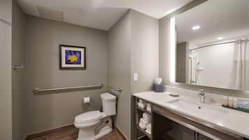 A modern bathroom with a toilet, sink, and handrails.