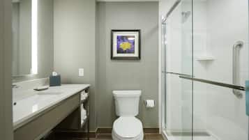 Een moderne badkamer met een wit toilet, een glazen douchecabine en een foto in een lijst aan de muur.