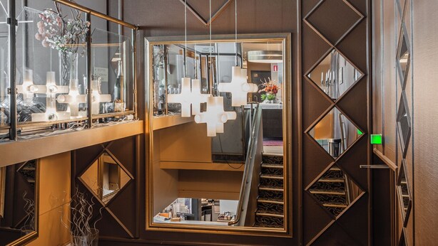 A modern interior with a staircase, decorative mirrors, and a patterned floor. - Teatterihotelli Riihimäki (Riihimaki)
