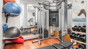 A gym with exercise equipment, a mirror, and a wall with a poster. - Teatterihotelli Riihimäki (Riihimaki)