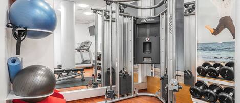 A gym with exercise equipment, a mirror, and a wall with a poster.